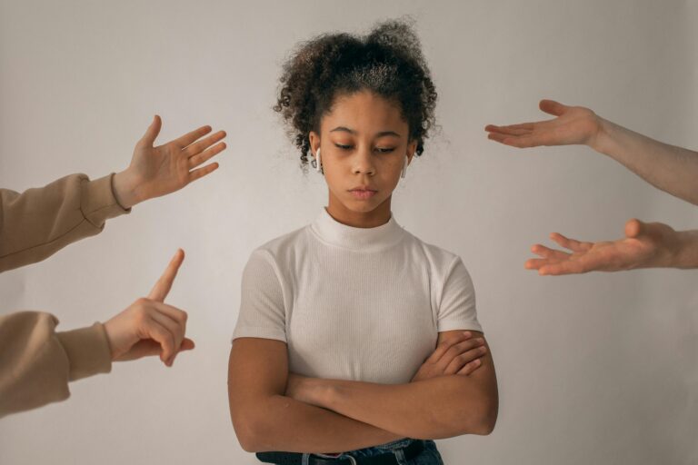 Illustration of why people become people pleasers, woman surrounded by pointing hands representing social pressure