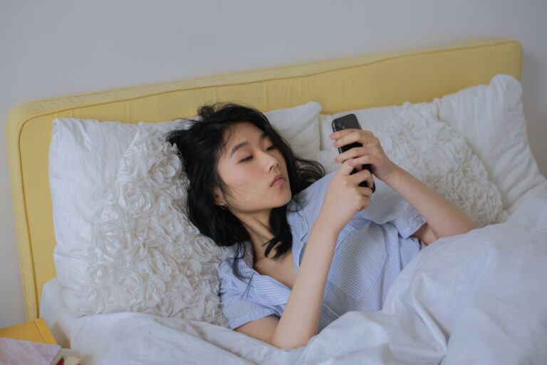 Woman lying in bed checking her phone first thing in the morning