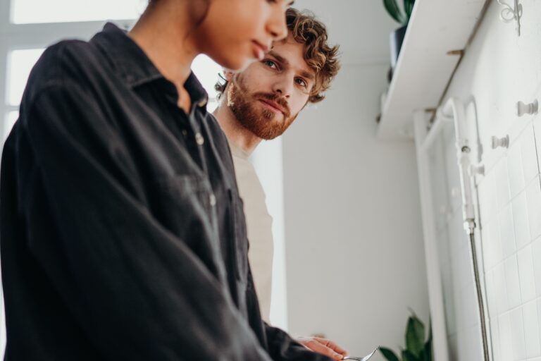 Two people standing close together, one looking toward the other who is turned away, illustrating how avoidance in relationships creates distance even between people who are present.