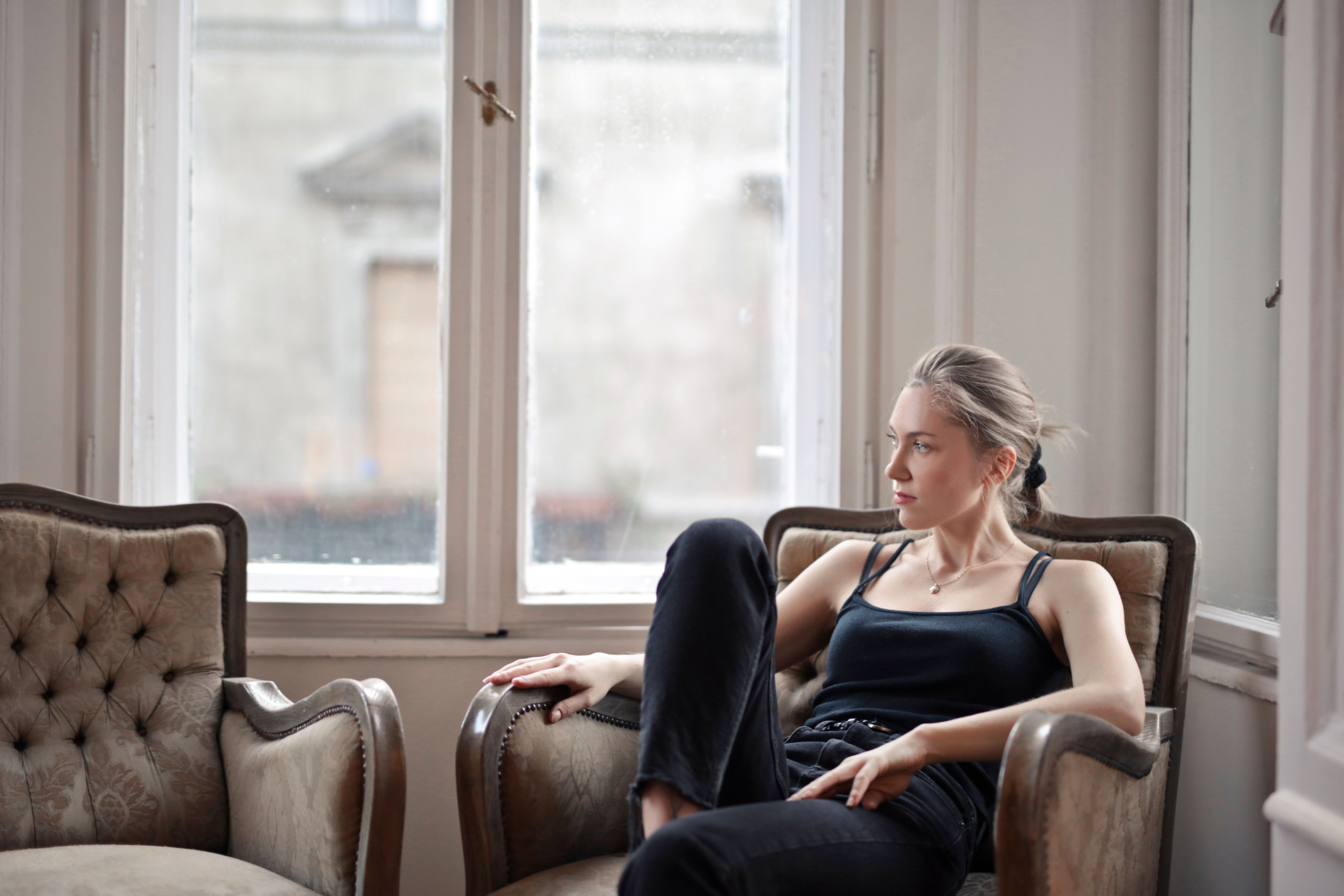 Woman sitting with a tense, guarded expression and closed posture, illustrating the fight response — the defensiveness and edge that build under the surface before any outward sign appears.
