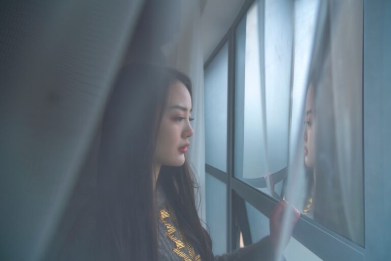 Woman looking at her own reflection in a window, illustrating the gap between how you appear to others and what shame tells you is true about yourself underneath.
