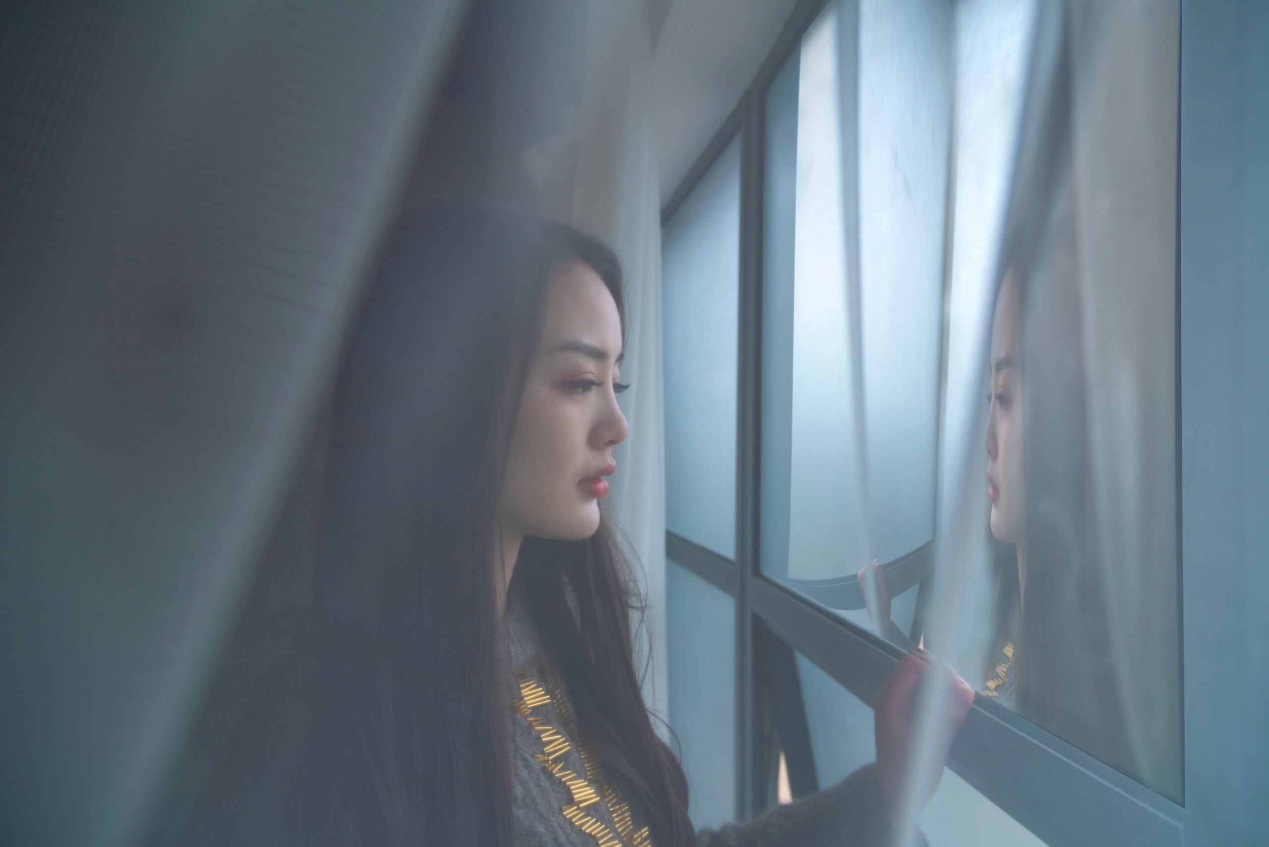 Woman looking at her own reflection in a window, illustrating the gap between how you appear to others and what shame tells you is true about yourself underneath.