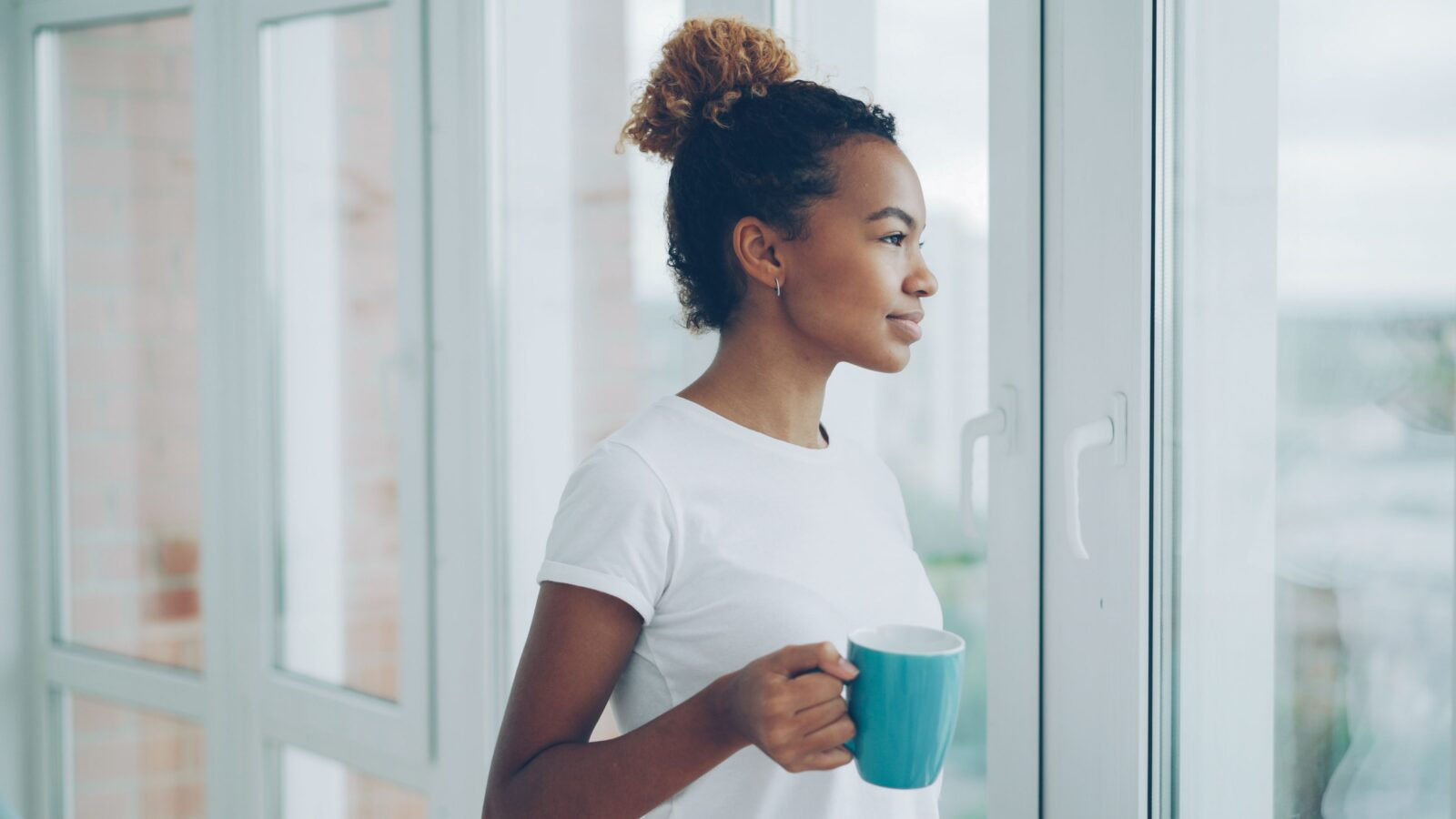Woman looking out window with coffee
